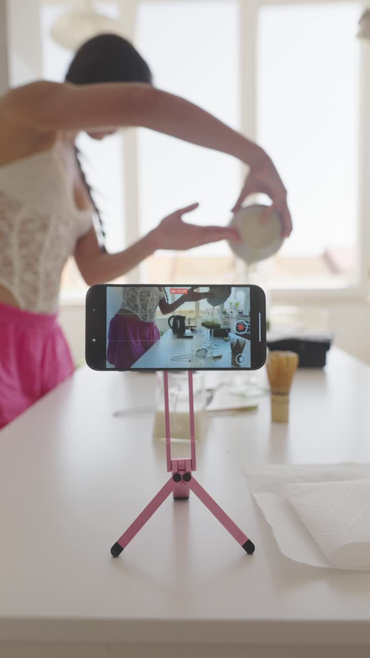A person filming a cooking video with a phone on a tripod