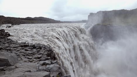 handheld shot of a mighty big waterfall with a large fall of the water, flowing very fast through