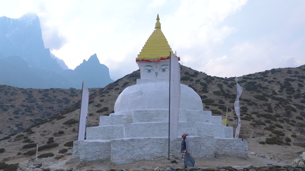 Drone view of a Sherpa woman performing religious ritual around a Buddhist Stupa at Dingboche, Everest trek. Himalayas and peaks in the backdrop, gentle wind adds to the scene Nepal tourism