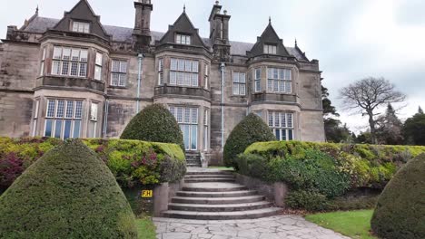 trimmed shrubs, staircase and grandiose facade of muckross house, national park killarney, ireland. tudor style architecture