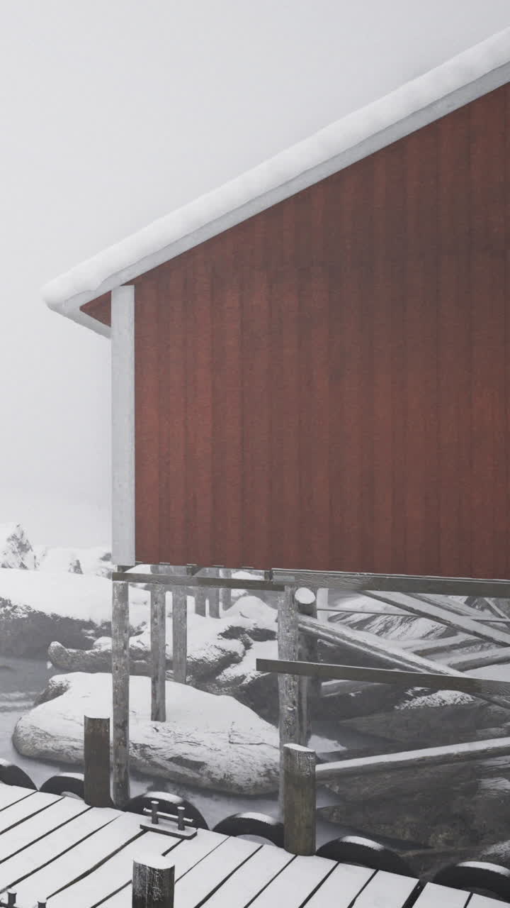 Red house by the sea in winter with snow and fog over the landscape