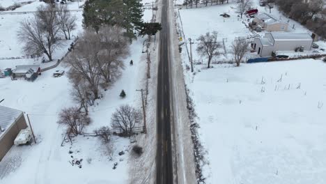 aerial shot of a plowed road cutting through rural farmland with snow covering the land