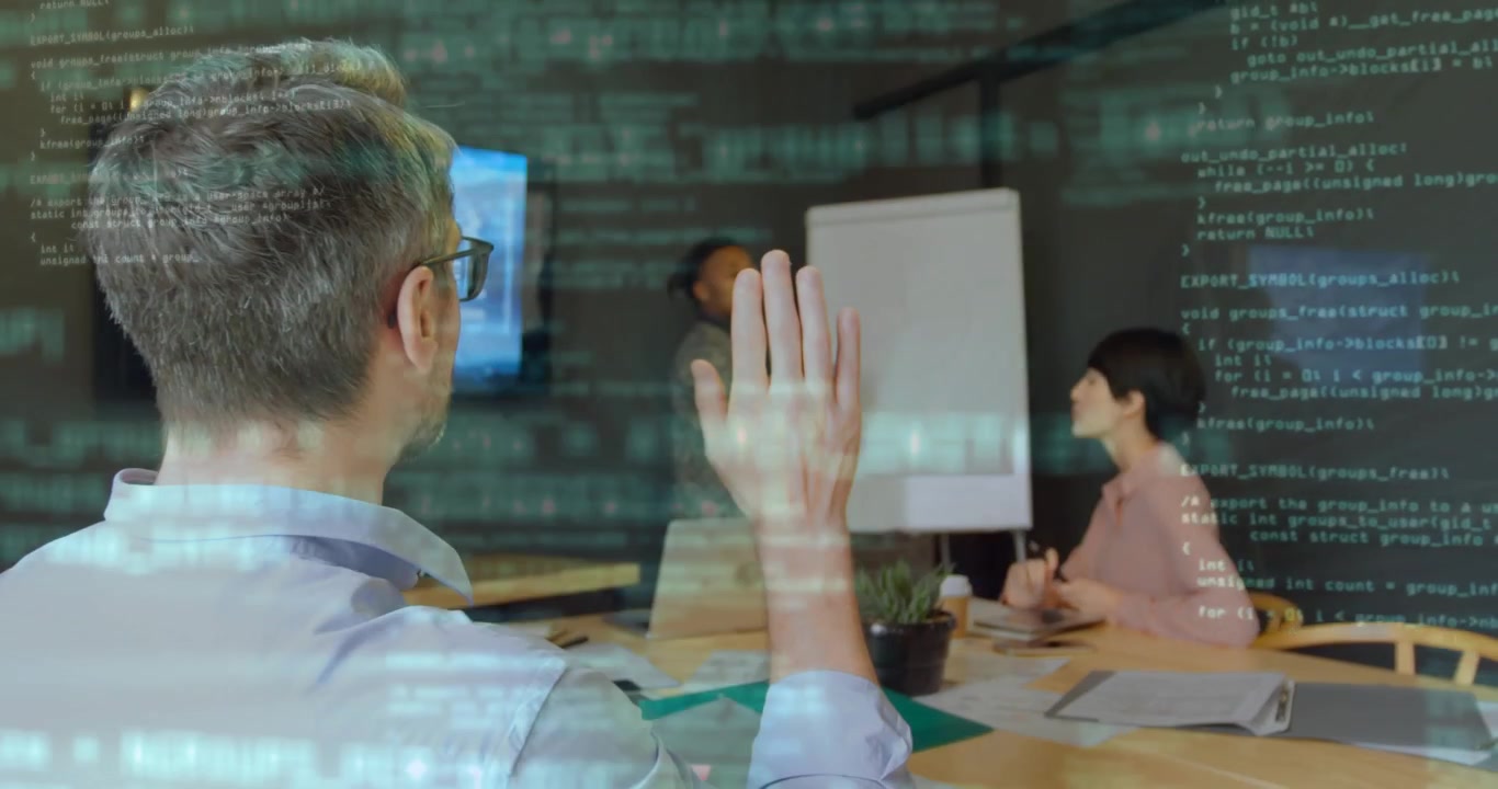 White man raising hand in IT asking question causing presenter pausing writing with code overlay