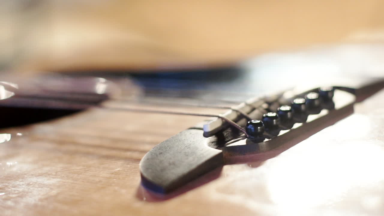 A big close up of a bass guitar Strings with its base, light reflections and focus shifting on the guitar