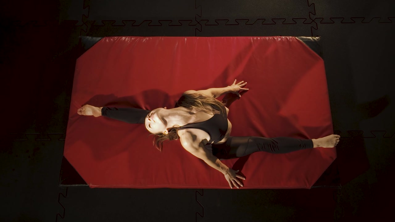 Flexible girl stretching on a mat. Top down view