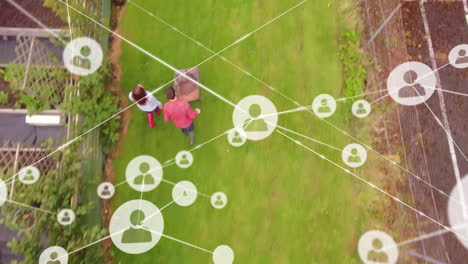 red de iconos de perfil contra vista aérea de pareja caucásica con carrito de jardín en el jardín