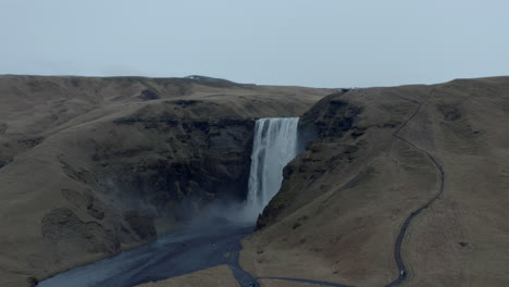 Slow-wide-rising-aerial-shot-of-tourists-around-Skogafoss-waterfall-Iceland
