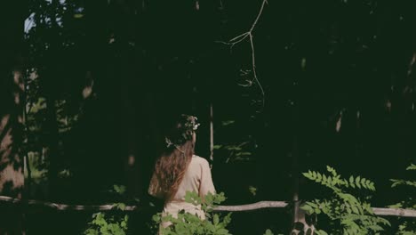 A-woman-during-Summer-Solstice-by-the-forest-with-her-flower-wreath,-colour-graded,-slow-motion