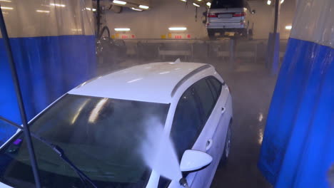 worker spraying water and washing a white opel, suv car, at a carwash, in sweden