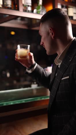 man drinking whiskey at a bar