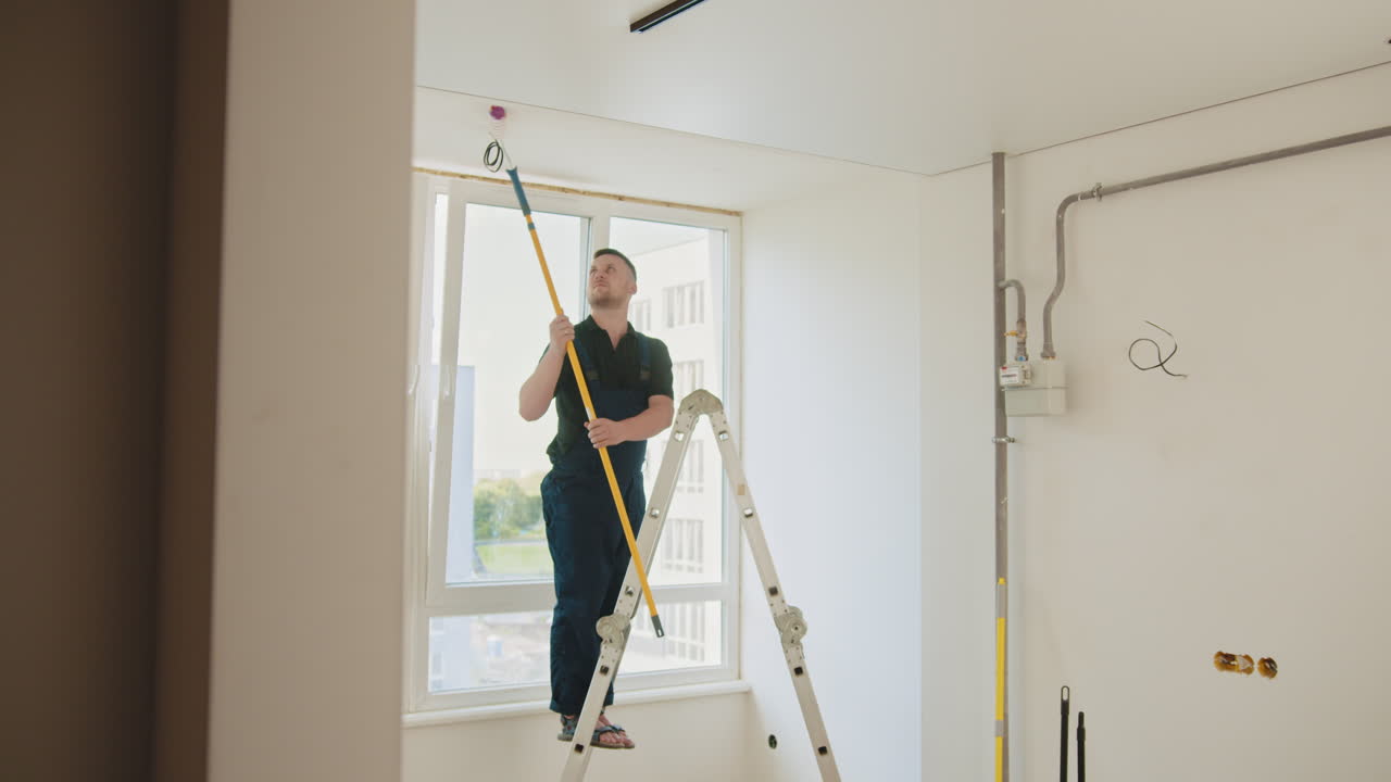 pintor trabajando en el techo de una habitación en construcción