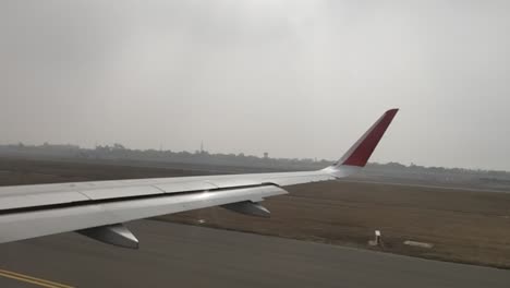 a view of the wing of an airplane through the window of an airplane taxiing on the runwaypreparing for the flight of the plane