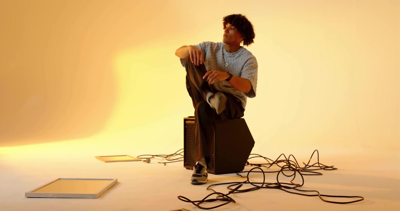 Músico masculino apoyado en un amplificador e iniciando ondas de agua sincronizando movimientos reflexivos de estudio.