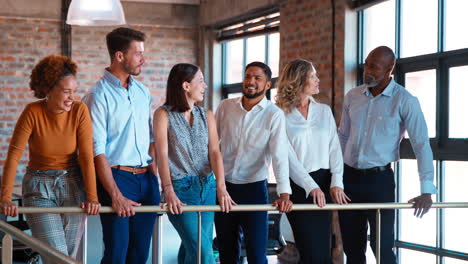 smiling multi-cultural business team standing together having informal meeting in modern office