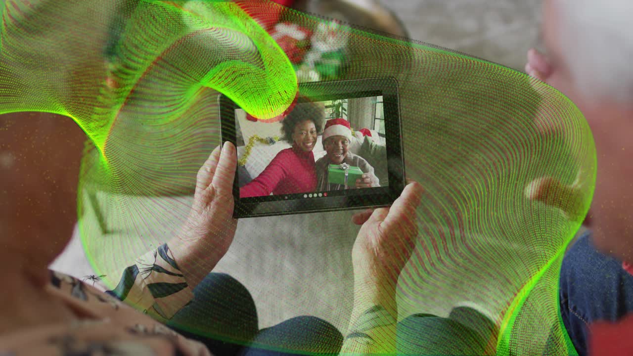 Una coppia di anziani in vacanza inclina un tablet per guardarlo, mentre un'onda verde oscura e poi rivela lo schermo