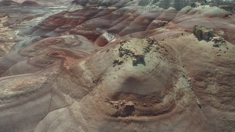 Dynamic-Aerial-View-of-Man-Climbing-Uphill-on-Scenic-Sandstone-Formations,-Utah-Desert,-Factory-Butte-Area