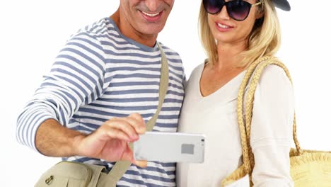 una pareja sonriente tomando una selfie desde un teléfono móvil contra un fondo blanco