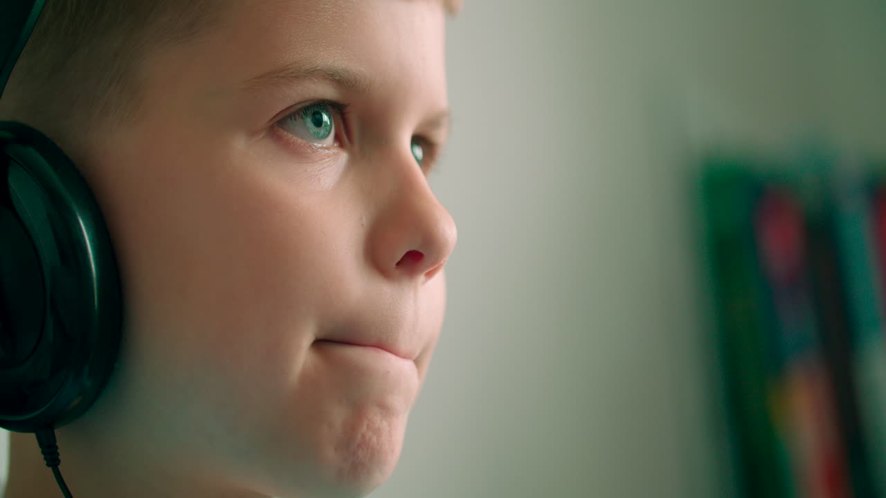 헤드폰을 끼고 온라인으로 비디오 게임을 하는 흥분되고 행복한 어린 아이의 라이프스타일 초상화