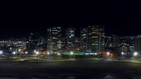 Dolly-Aéreo-Izquierda-Tiro-De-Luces-Brillantes-En-Los-Rascacielos-Frente-Al-Mar-En-Iquique,-Chile