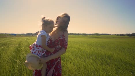 close-up mom in summer dress in field is holding little daughter