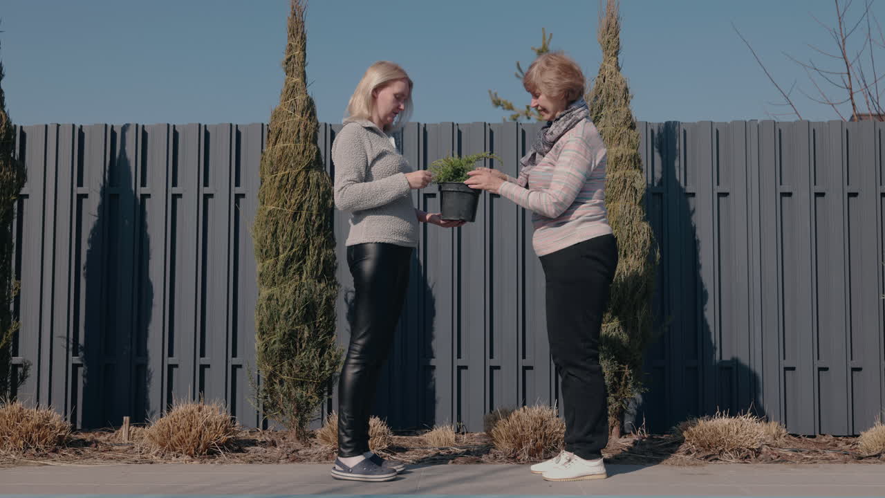 dos mujeres compartiendo una planta en maceta en el jardín