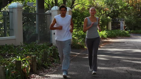 a jogging couple run together down the street