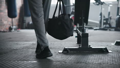 a man walks into a gym with a duffel bag