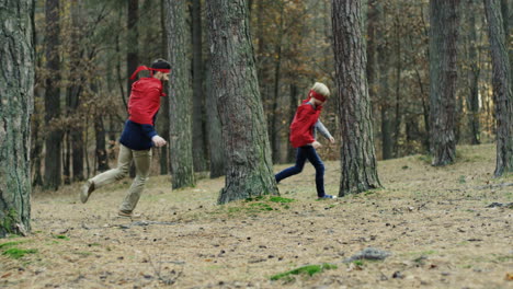 caucasian cheerful father and son in red capes running in the forest and playing they being superheroes