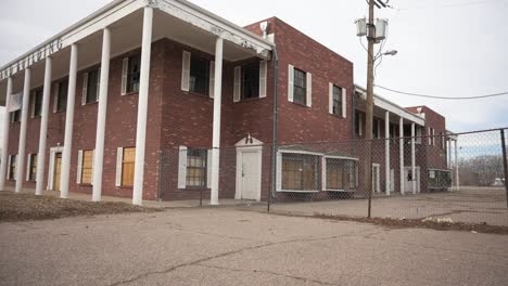 Abandoned-brick-school-with-boarded-up-windows-during-a-cloudy-and-overcast-day,-static