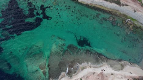 top down view of munxar window, limestone cliff side, turquoise water, green fields, waves splashing, malta island