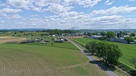 Una-Vista-De-Drones-De-Una-Locomotora-De-Vapor-Con-Vagones-De-Pasajeros-Acercándose-Al-Campo-En-Un-Hermoso-Día-De-Verano