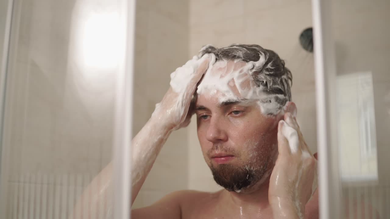 Uomo che si lava i capelli sotto la doccia