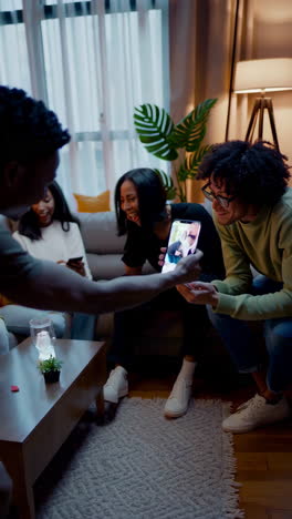friends socializing and sharing content on mobile devices in a living room
