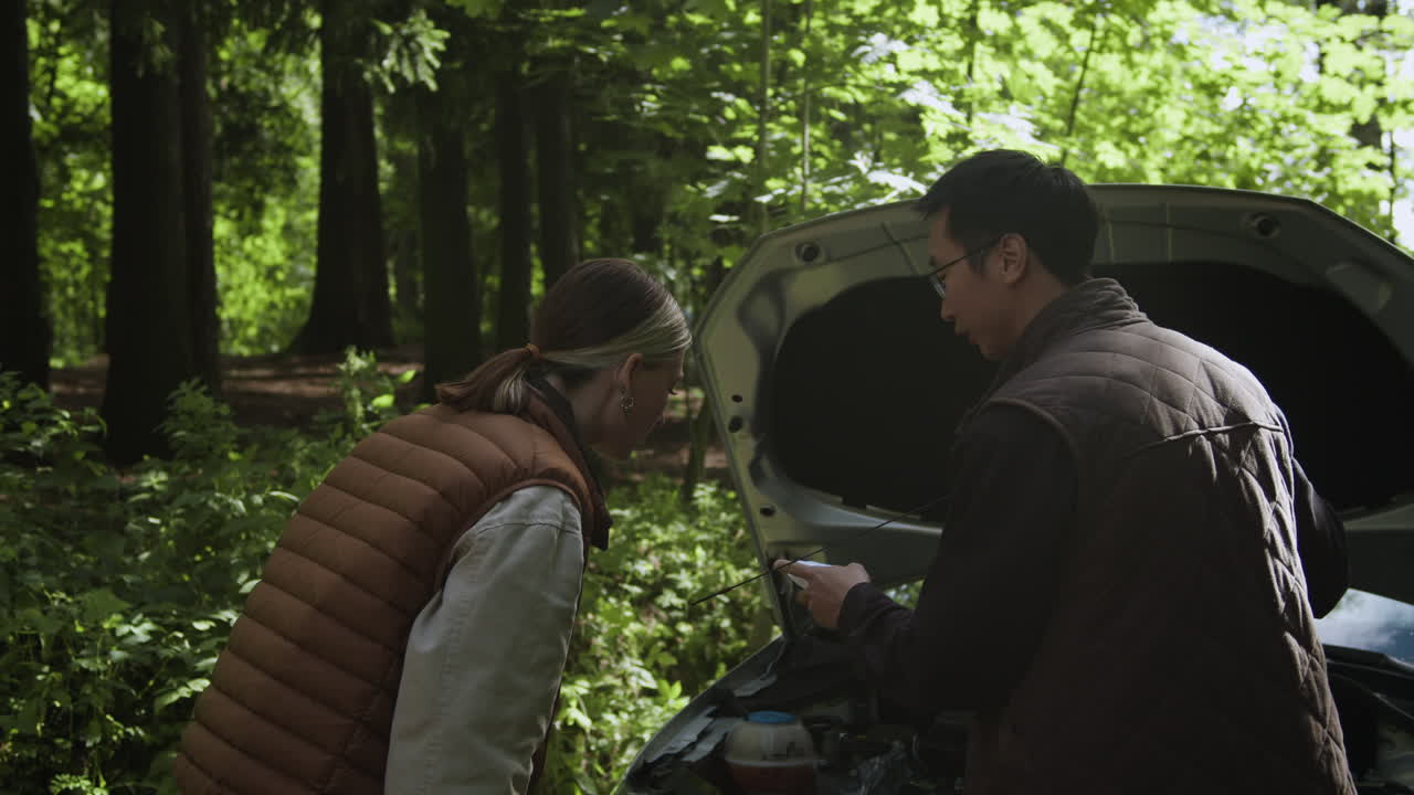 People inspecting a car in a forest