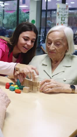 Elderly woman playing blocks with young woman