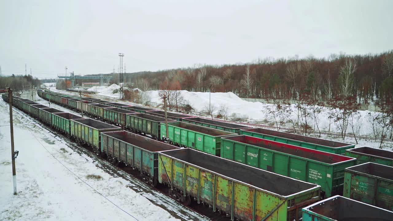 Long rows with old cargo containers for the transport of imports and exports stand on the edge of the forest in the winter on the border zone. Aerial view.