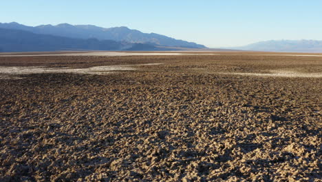 drone flight over rugged and harsh terrain of large salt pan on floor of death valley national park