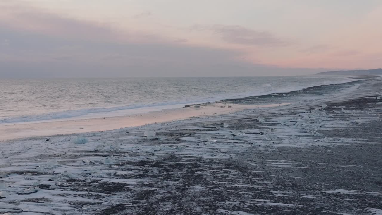 일몰 때 눈으로 뒤덮인 다이아몬드 해변에 파도가 부서지는 공중 풍경