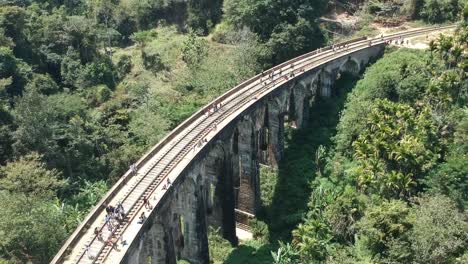 aerial over nine arch bridge with visitors walking across in sri lanka. follow shot