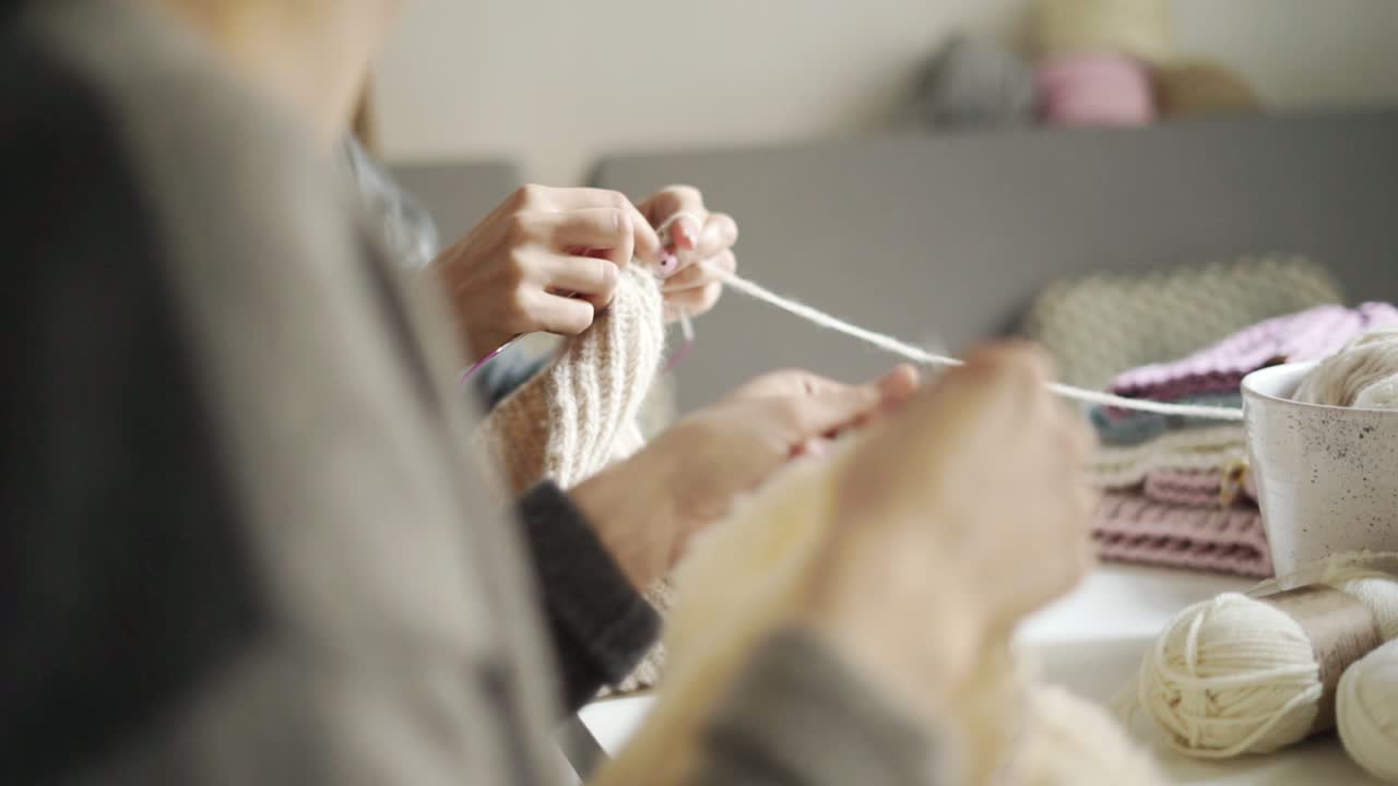 모직 옷을 뜨개질하는 여성 손을 닫습니다. 두 여자 뜨개질 의류