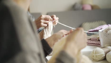 close up of female hands knitting woolen clothes. two woman knitting clothing