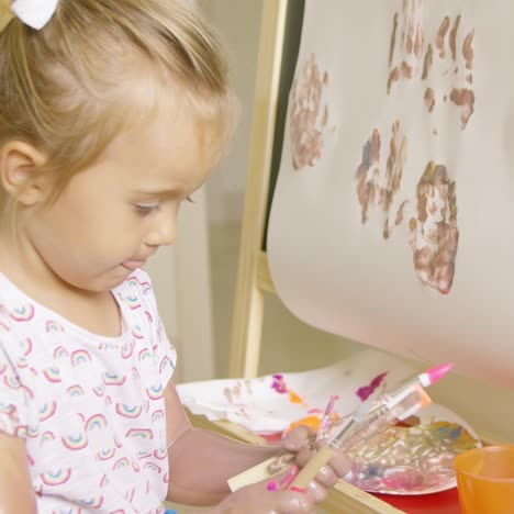 cute little girl choosing a paint brush