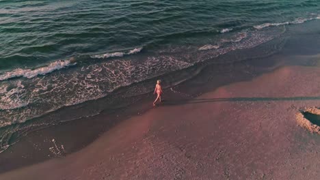 Woman-walking-on-the-beach-at-dusk