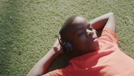 listening to music, boy relaxing on grass with headphones, enjoying leisure time