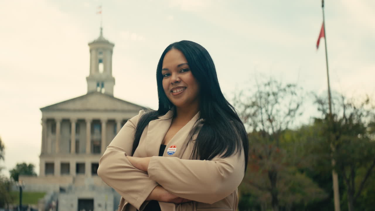 Portrait of a woman with voting sticker in front of a government building