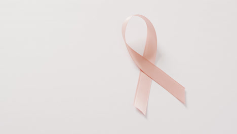 Video-of-peach-pink-uterine-cancer-ribbon-on-white-background