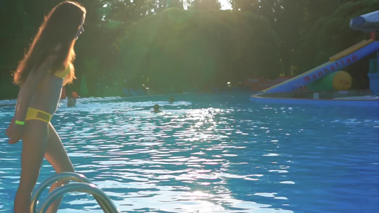 Girl and splashes in the pool on a sunny day