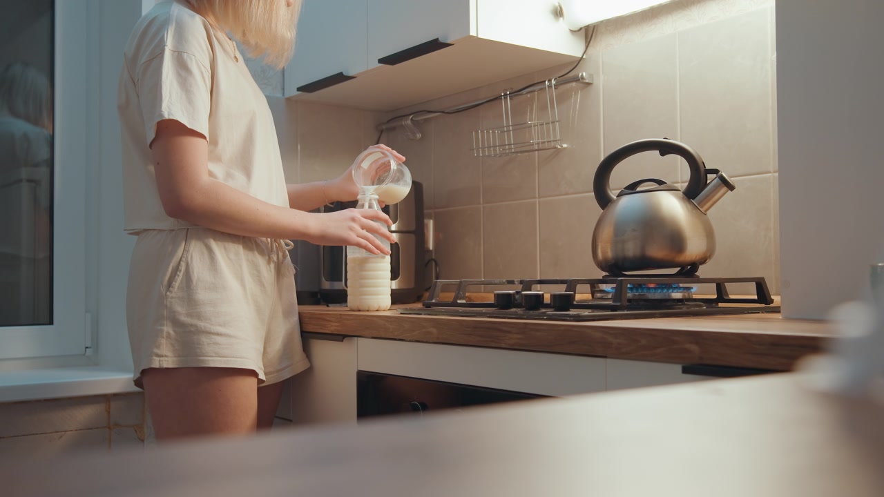 Morning scene with woman pouring milk. Woman in comfortable attire pours milk into jar during breakfast. Relaxed woman in casual clothing serves milk into jar while preparing morning coffee