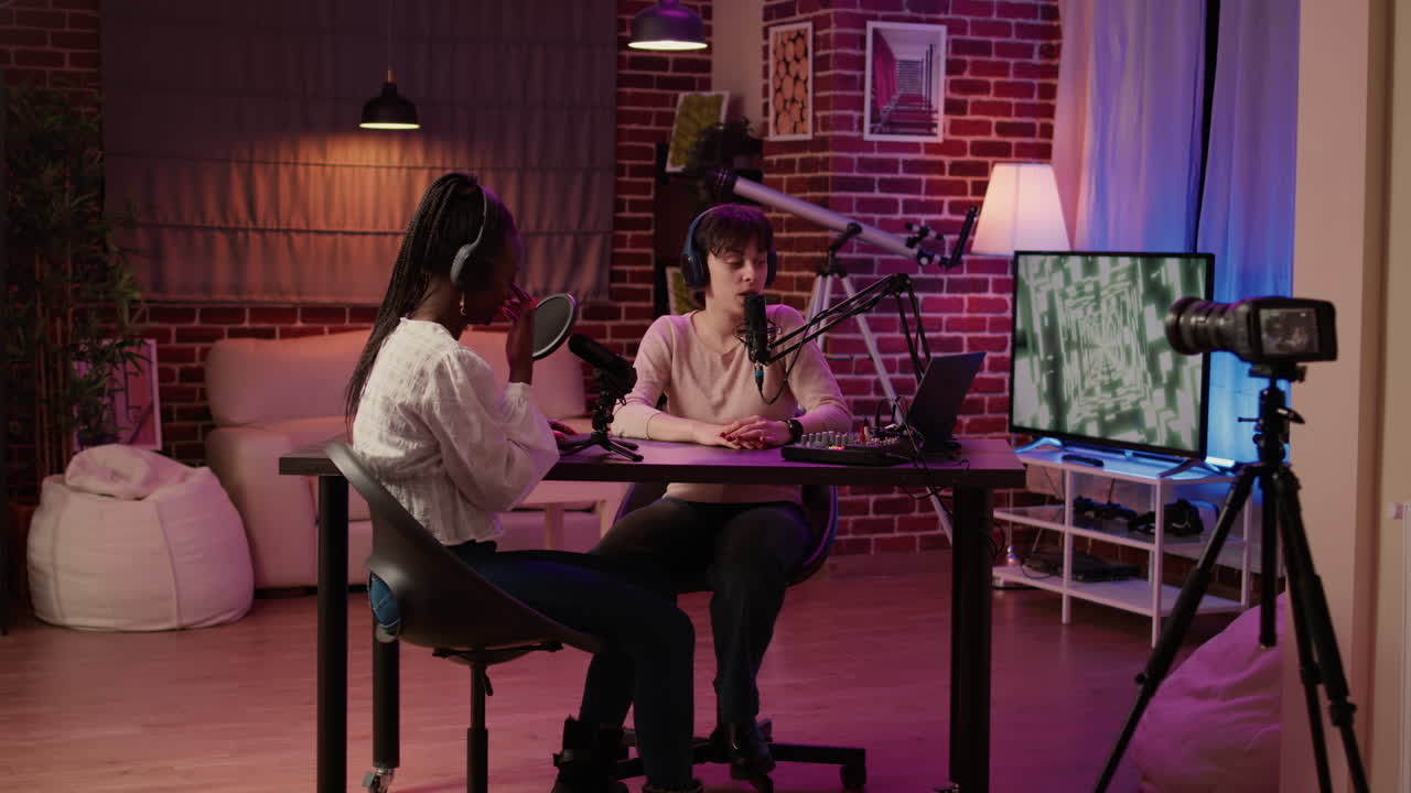 Two women recording interview using professional microphone in front of digital camera