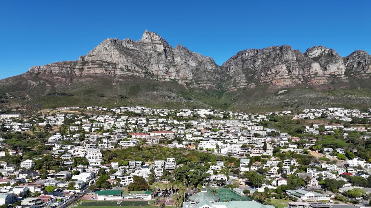 Aerial drone footage of Camps Bay Beach on the Atlantic Seaboard in Cape Town, South Africa iconic mountain backdrop of Lion’s Head and the Twelve Apostles